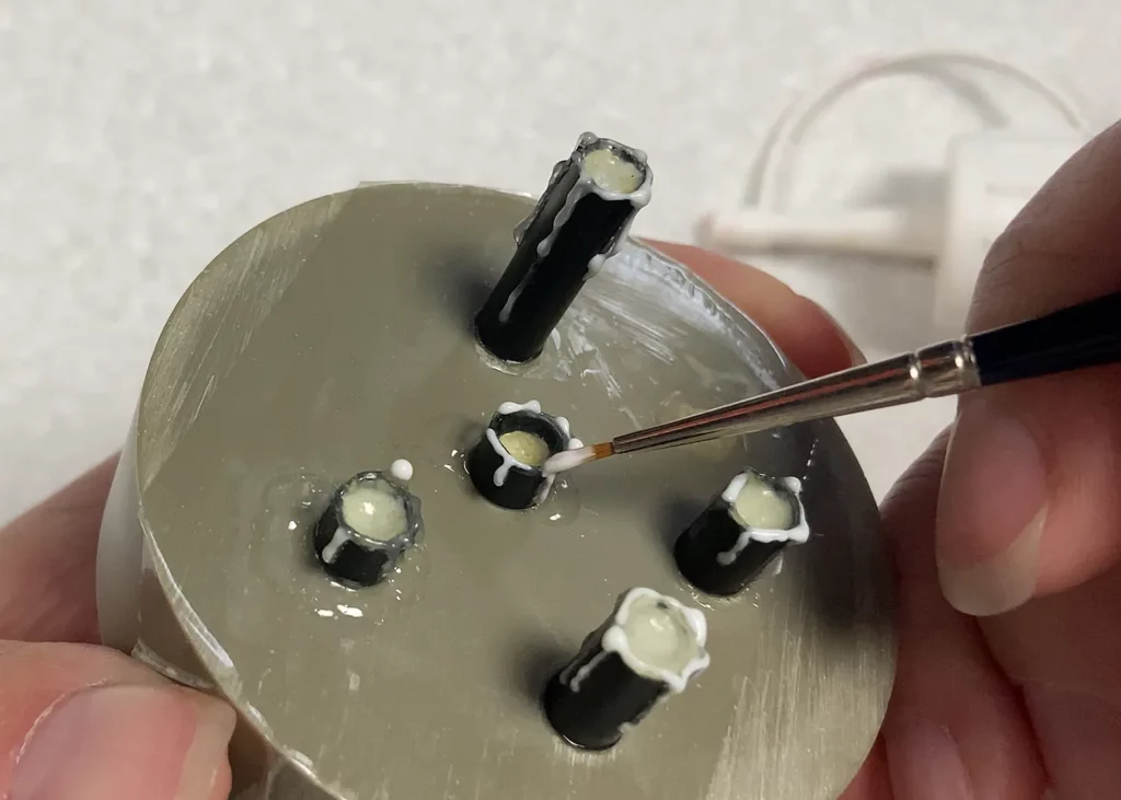 Close-up of adding melted wax to the top of miniature candles using old brush - step-by-step tutorial by Minichix Studio.