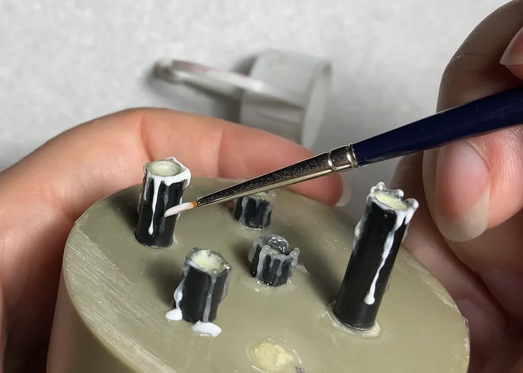 Layering melted wax drips on miniature candle using old brush - step-by-step tutorial by Minichix Studio.