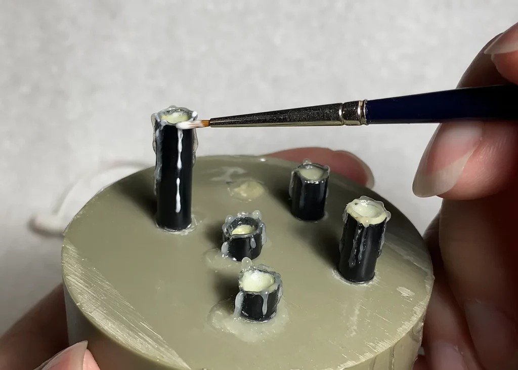 Shaping melted wax drips on miniature candle using old brush - step-by-step tutorial by Minichix Studio.