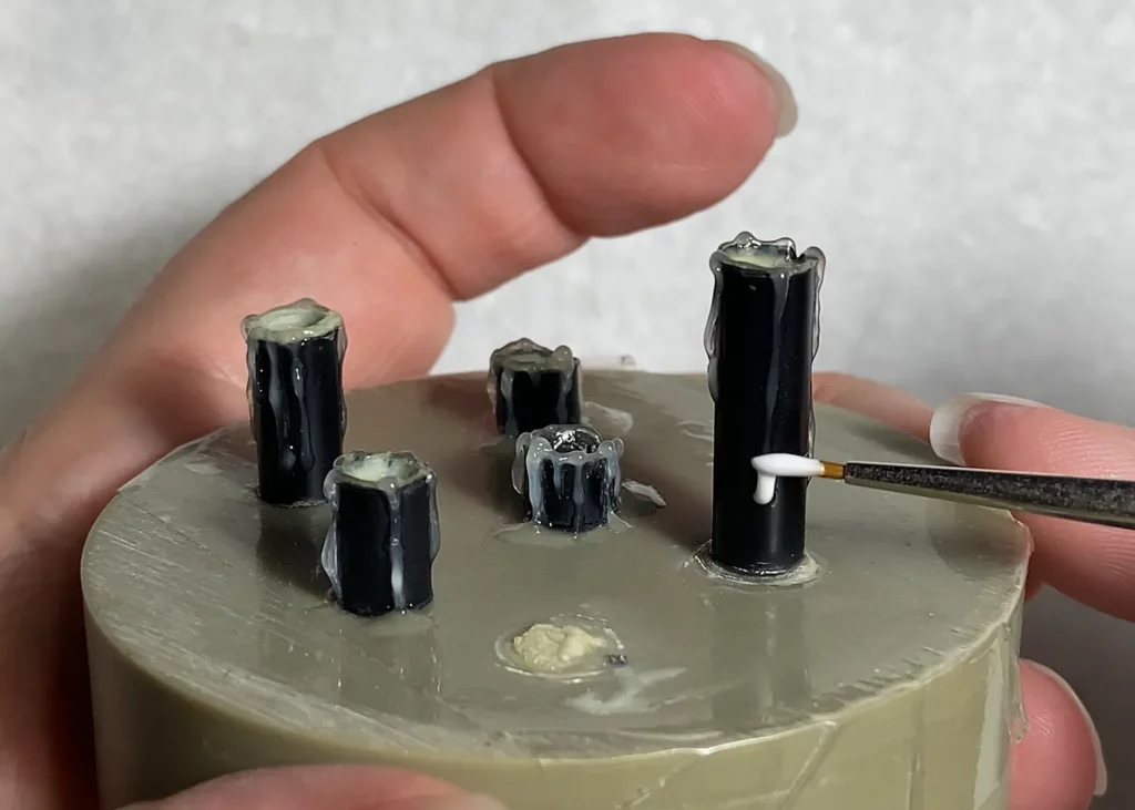 Close-up of applying melted wax drips to a miniature candle with old brush - step-by-step tutorial by Minichix Studio.
